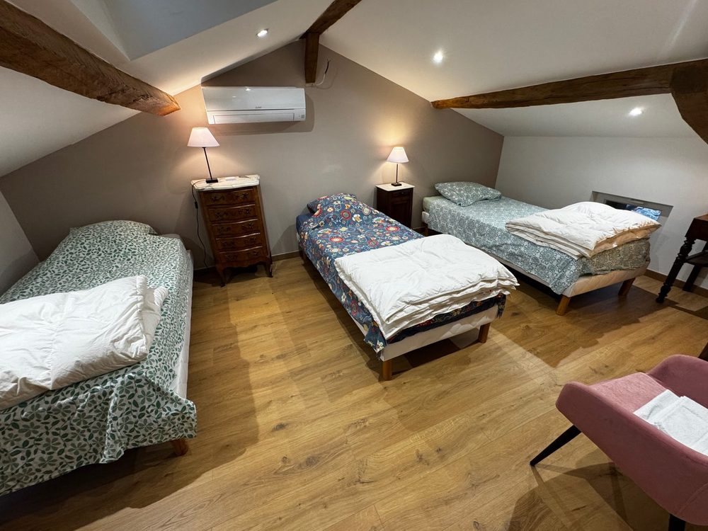 Chambre de trois lits simples sous les poutres