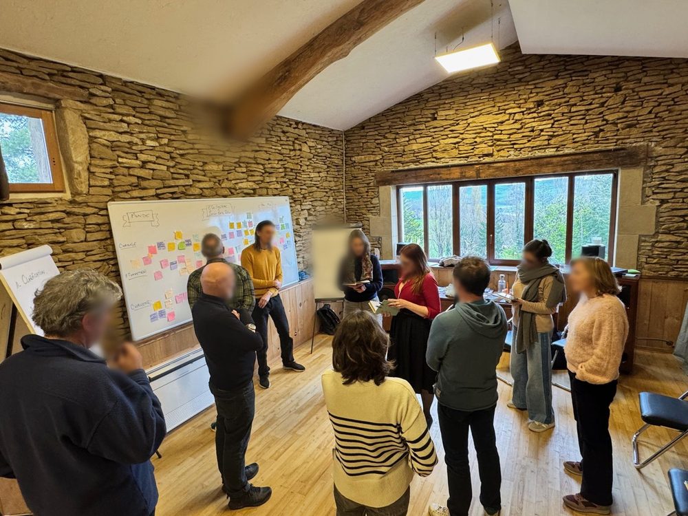 Un groupe debout devant un mur de post-it dans la grande salle