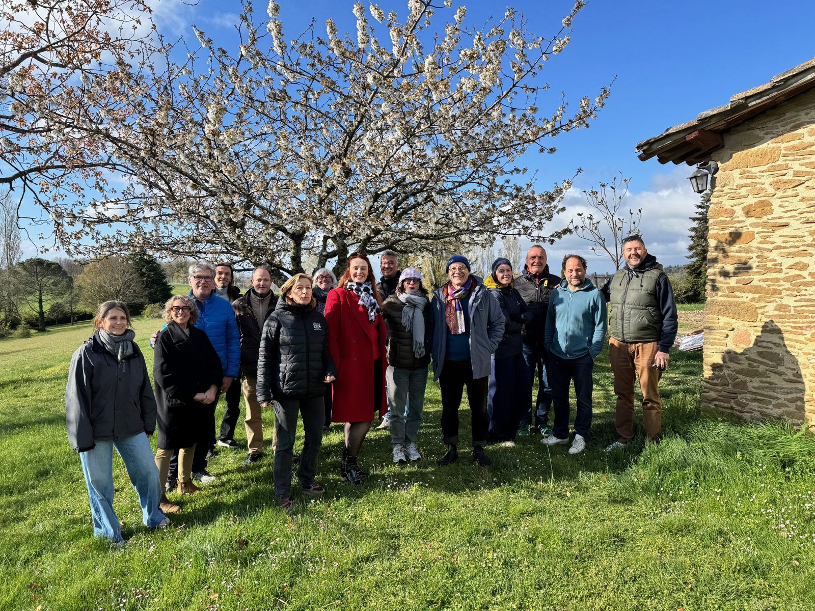 Un grand groupe réuni sous le cerisier en fleurs, devant la maison
