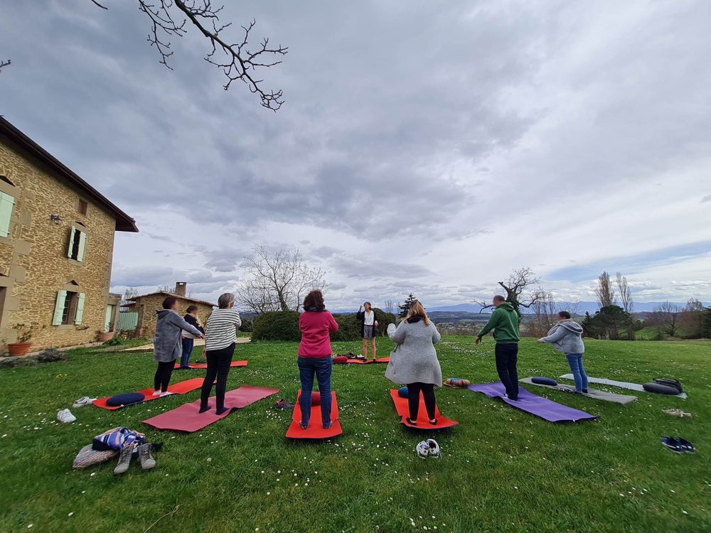 Séance de yoga sur tapis dans le parc, la maison en fond